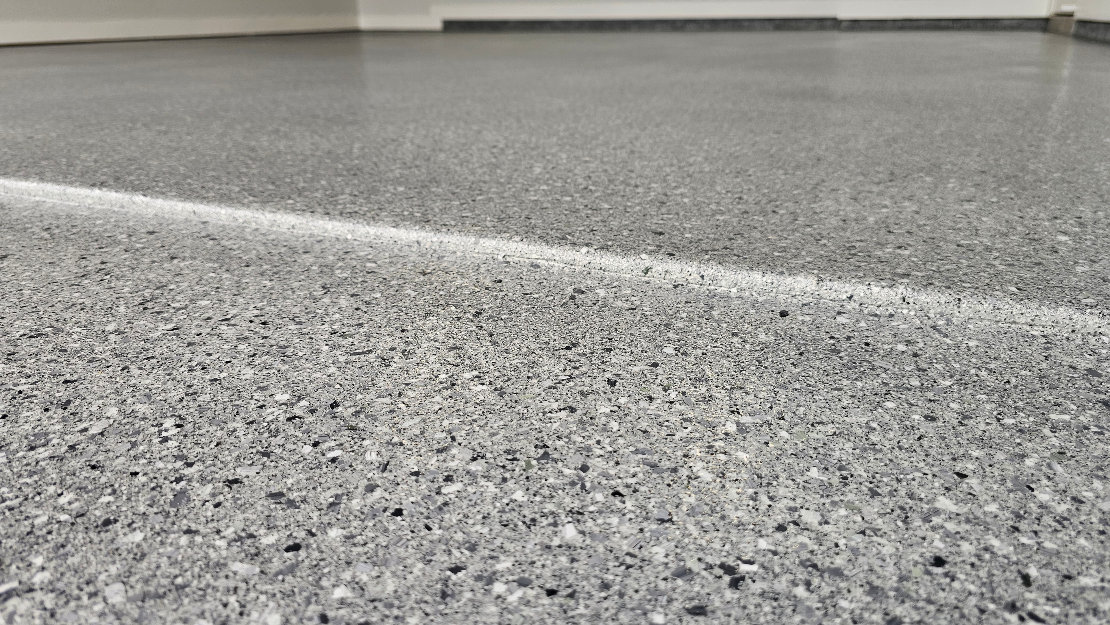 Grey flake epoxy floor close-up with white stripe detail
