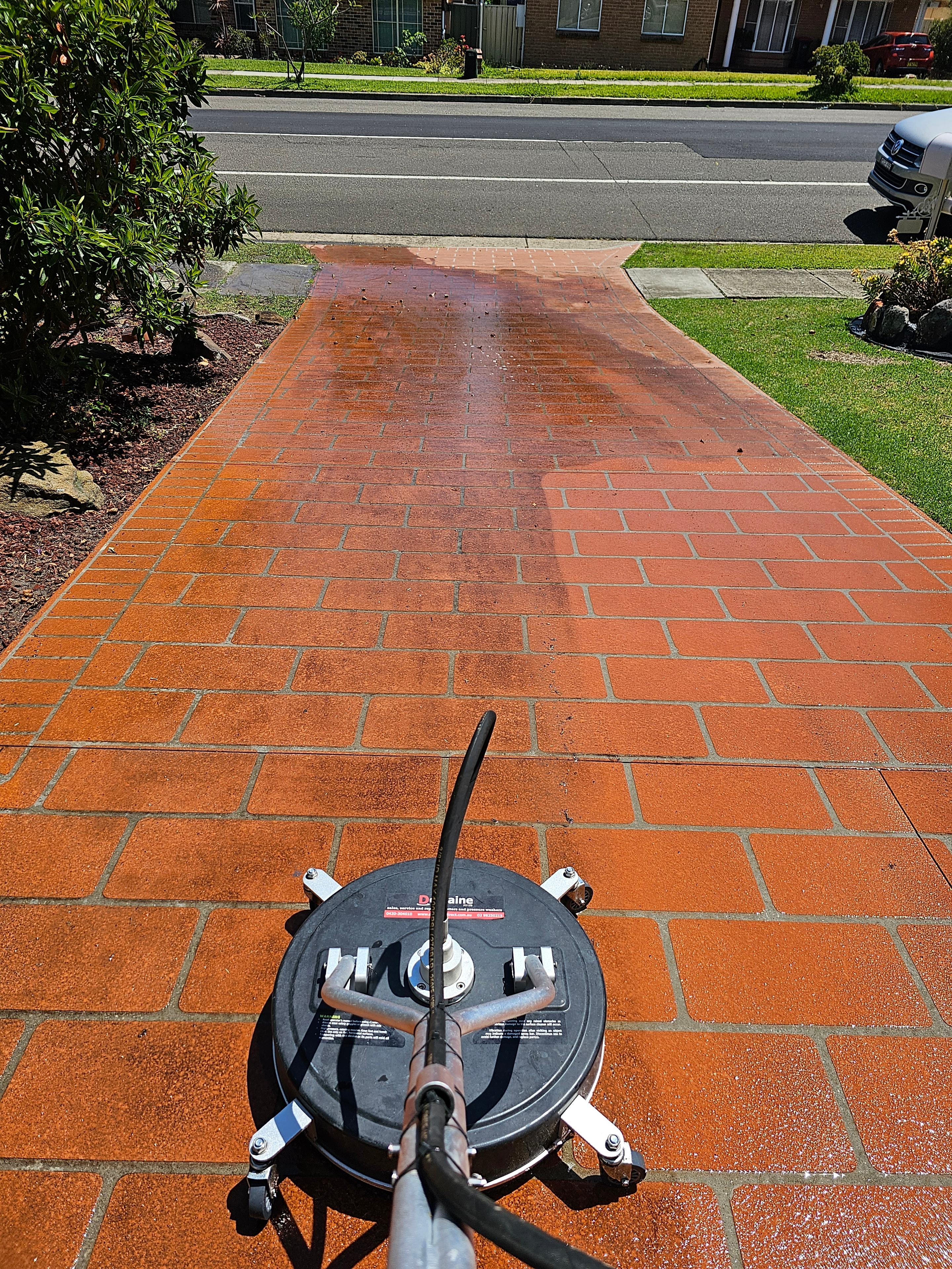Brick paver driveway being pressure cleaned with surface cleaner attachment